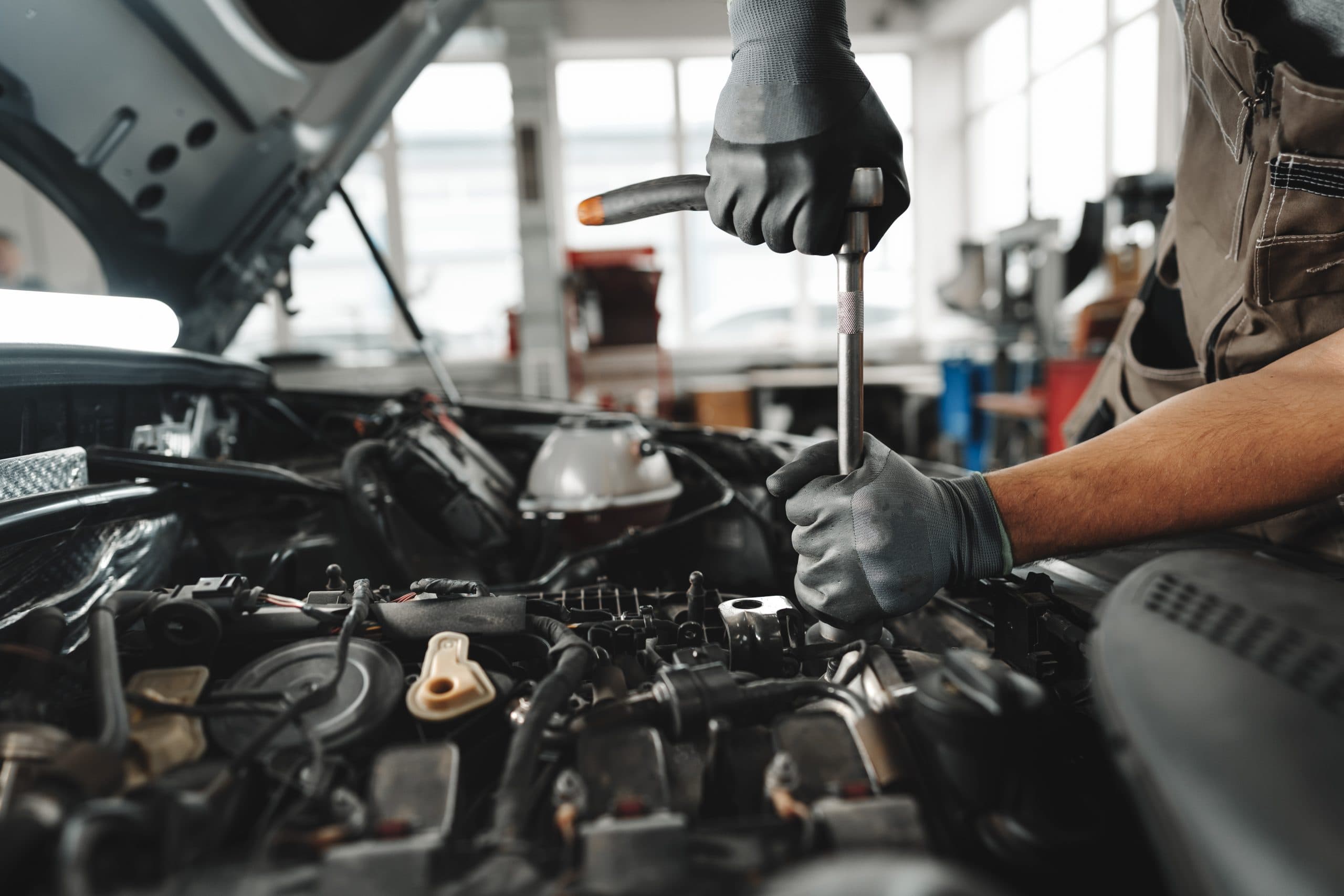 Professional mechanic working under the hood of a car in a workshop
